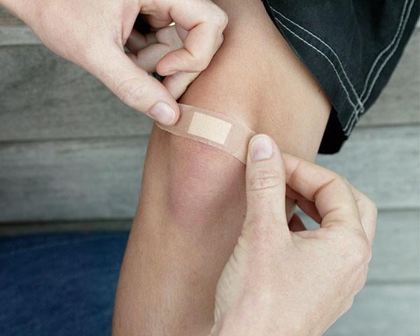 Covering a minor wound on a knee with a Band-Aid® bandage
